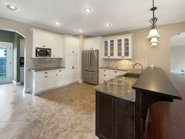 kitchen featuring white cabinets, kitchen peninsula, stainless steel appliances, tasteful backsplash, and sink