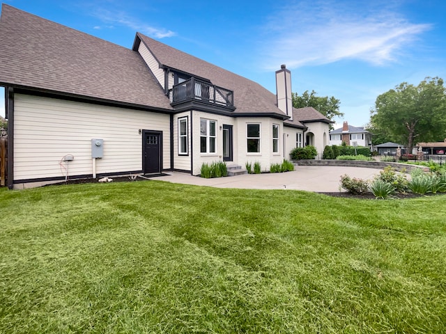 rear view of property with a patio, a balcony, and a lawn