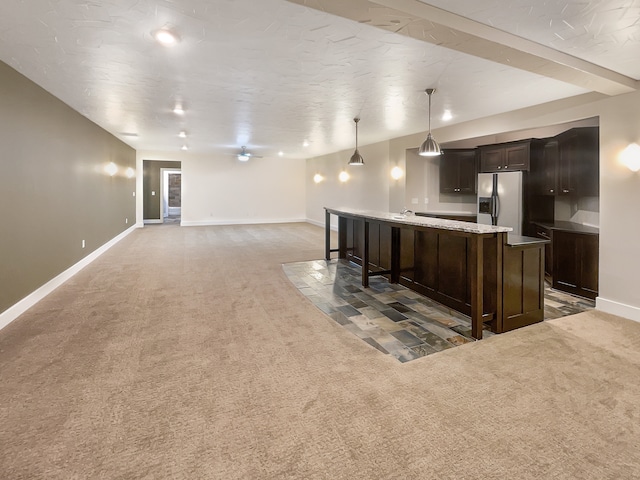 kitchen featuring dark brown cabinets, a center island with sink, stainless steel refrigerator with ice dispenser, pendant lighting, and carpet