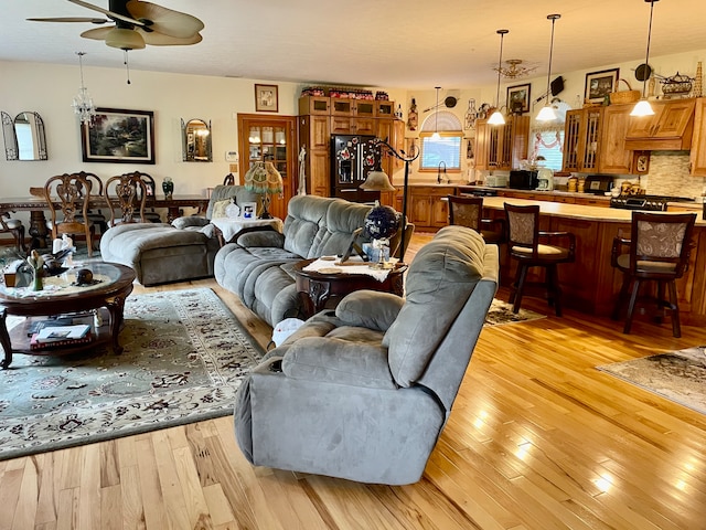 living room with ceiling fan, sink, and light hardwood / wood-style floors