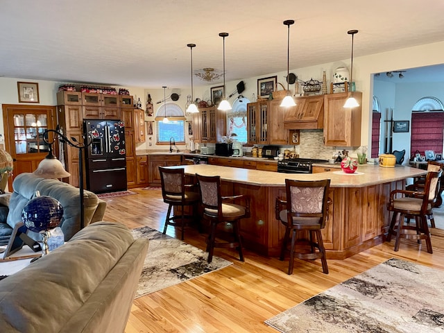 kitchen with a breakfast bar, light wood-type flooring, and black appliances