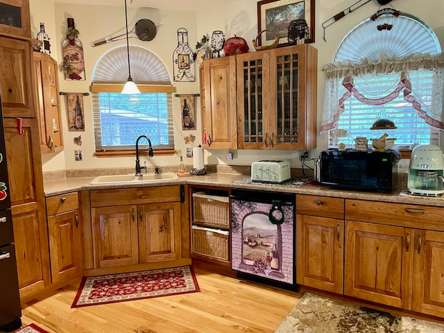 kitchen with wine cooler, sink, decorative light fixtures, and light hardwood / wood-style flooring