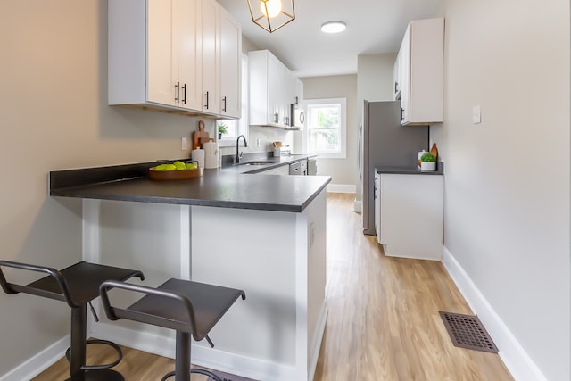 kitchen featuring sink, light hardwood / wood-style floors, white cabinets, and kitchen peninsula