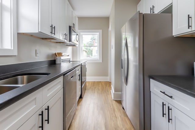 kitchen with white cabinets, light wood-type flooring, and appliances with stainless steel finishes