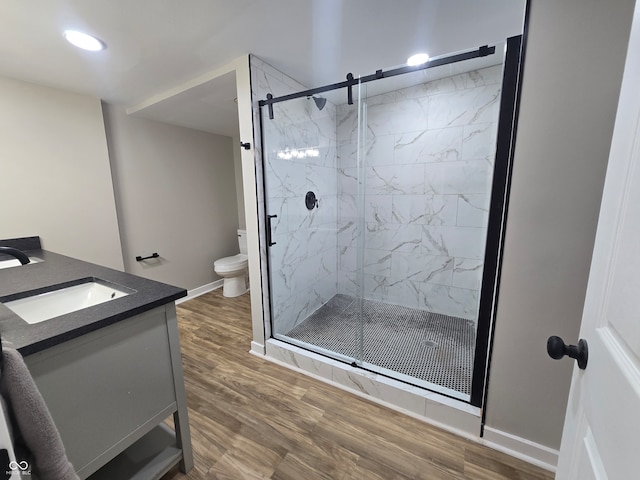 bathroom with walk in shower, hardwood / wood-style floors, toilet, and vanity