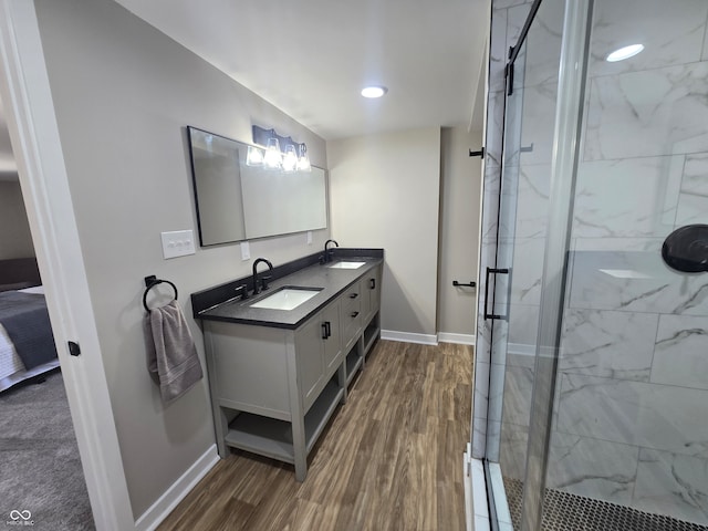 bathroom with walk in shower, vanity with extensive cabinet space, dual sinks, and wood-type flooring