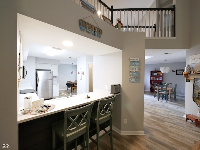 interior space featuring decorative light fixtures, white cabinets, hardwood / wood-style floors, and stainless steel appliances