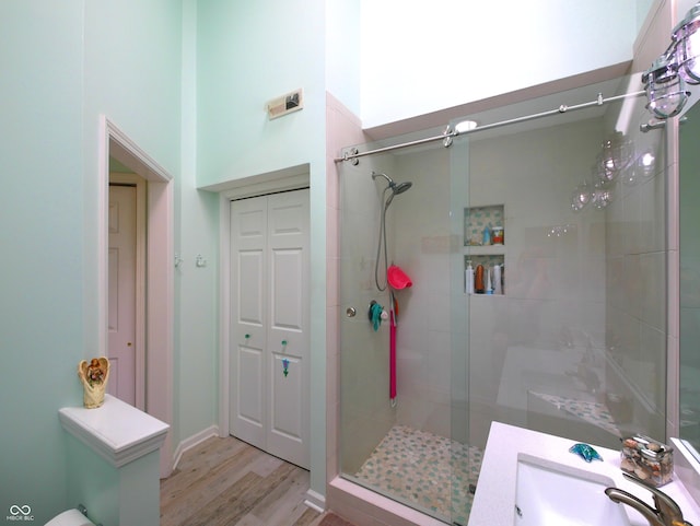 bathroom with wood-type flooring, a high ceiling, vanity, and a shower with shower door