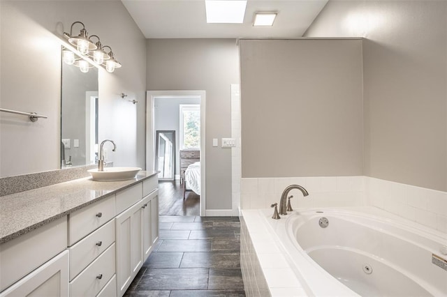 bathroom with tile floors, a relaxing tiled bath, vanity, and a skylight