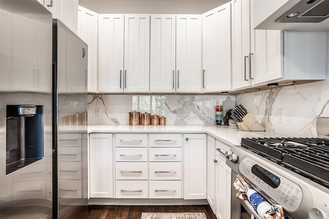 kitchen with wall chimney exhaust hood, tasteful backsplash, white cabinetry, and appliances with stainless steel finishes