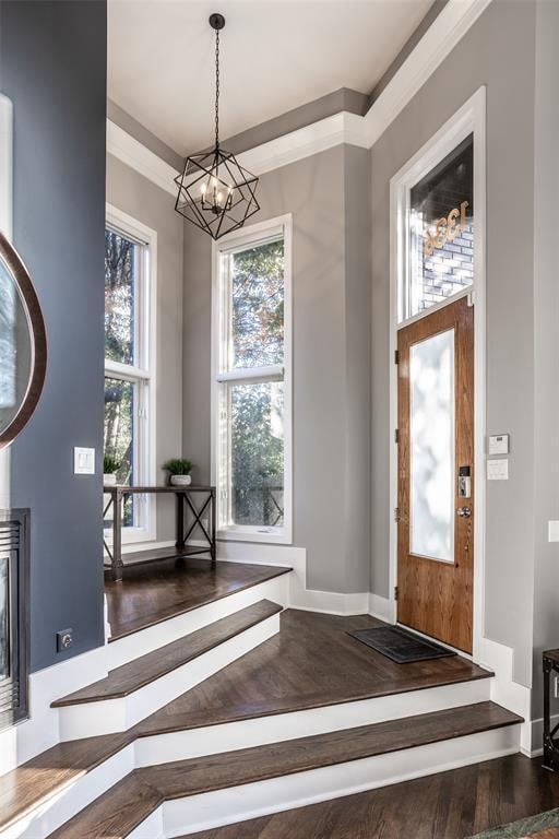 entryway featuring dark wood-type flooring, plenty of natural light, and a chandelier