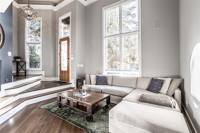 living room featuring ornamental molding, a towering ceiling, hardwood / wood-style flooring, and a chandelier