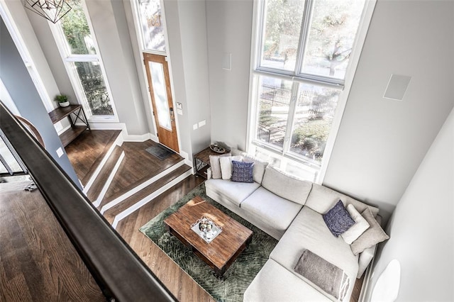 living room featuring a towering ceiling and dark wood-type flooring