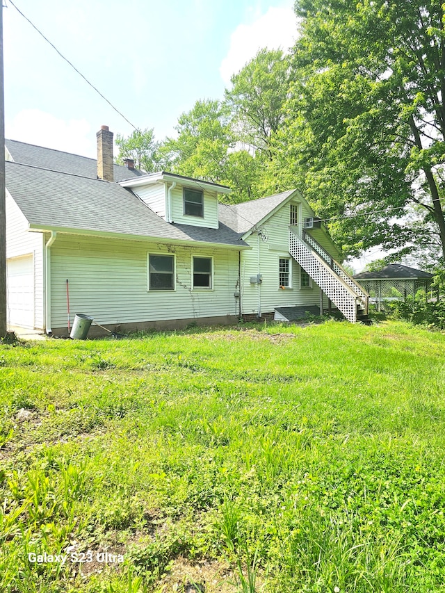 rear view of property with a garage and a lawn