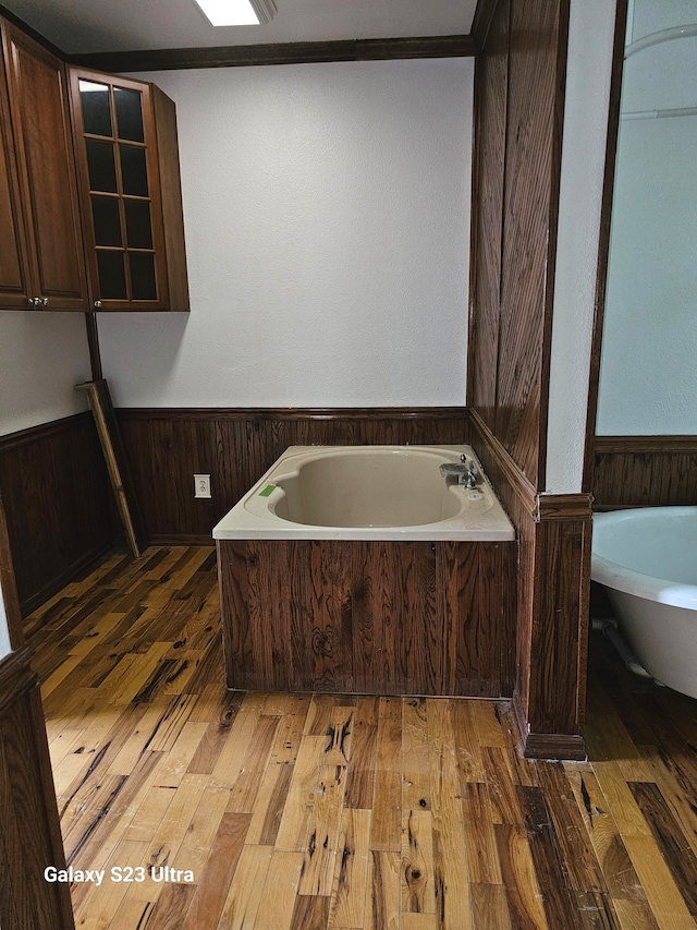 bathroom featuring wood-type flooring and a bath to relax in