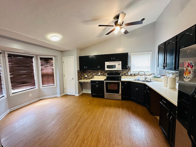 kitchen featuring appliances with stainless steel finishes, tasteful backsplash, light wood-type flooring, and vaulted ceiling