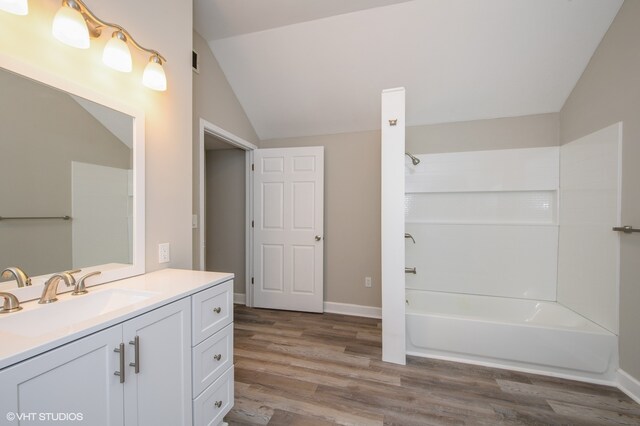 bathroom with bathtub / shower combination, lofted ceiling, vanity, and wood-type flooring