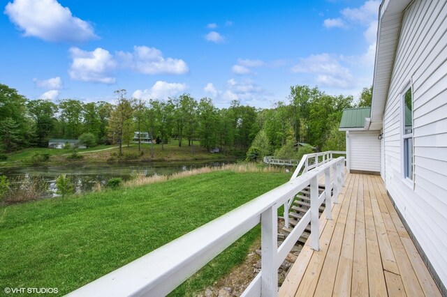 wooden terrace featuring a water view and a yard