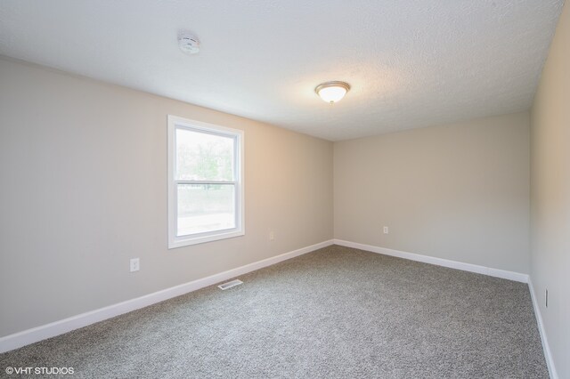 carpeted spare room with a textured ceiling