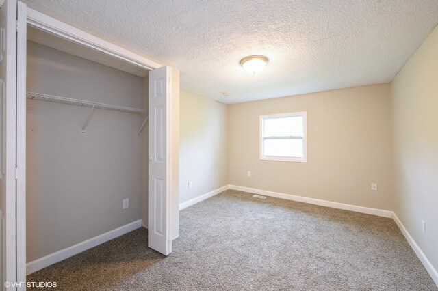 unfurnished bedroom featuring a closet, carpet floors, and a textured ceiling