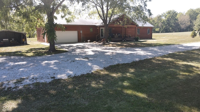 exterior space featuring a garage, a carport, a front lawn, and an outdoor structure