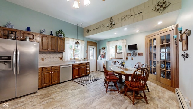 kitchen featuring decorative light fixtures, light tile flooring, stainless steel appliances, backsplash, and baseboard heating