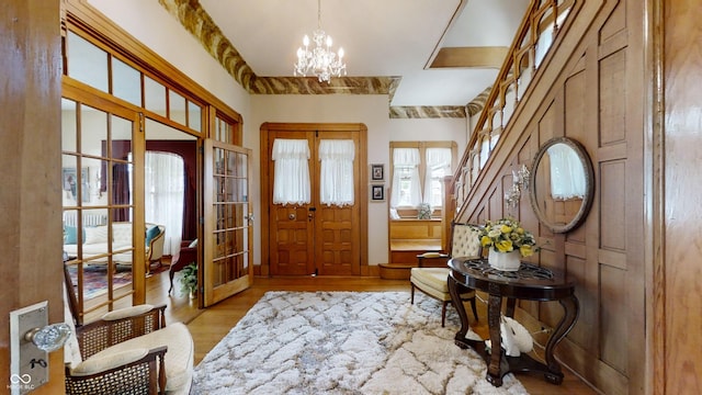 foyer featuring light hardwood / wood-style floors, french doors, and an inviting chandelier