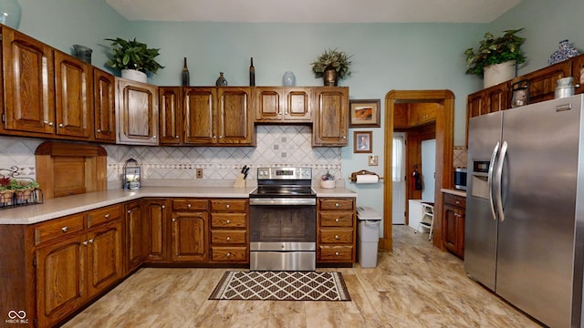 kitchen featuring stainless steel appliances, backsplash, and light tile floors