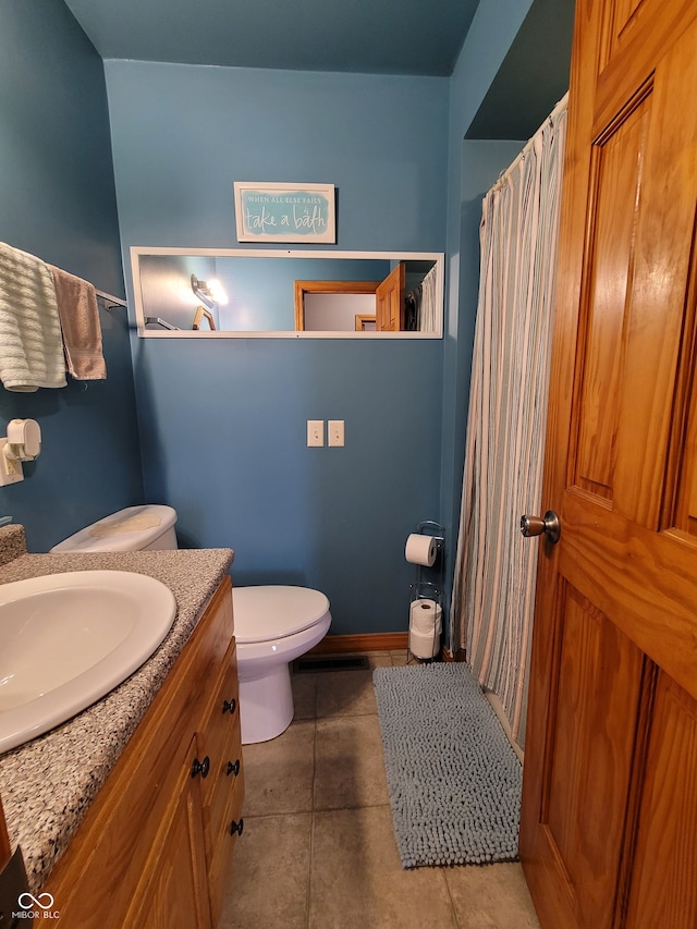 bathroom featuring tile flooring, vanity, and toilet