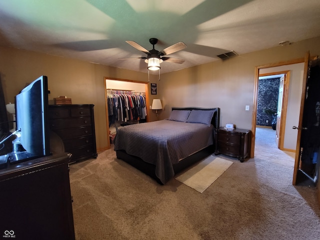 carpeted bedroom with a spacious closet, a closet, and ceiling fan