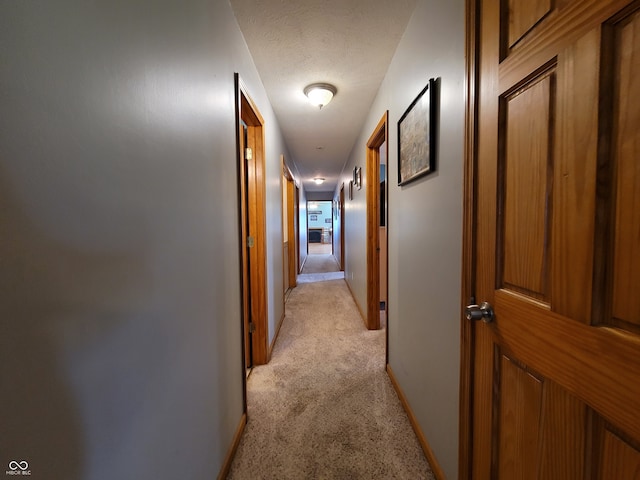 hallway featuring a textured ceiling and light carpet