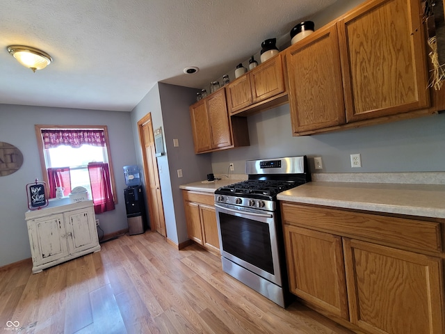 kitchen featuring light hardwood / wood-style floors, a textured ceiling, and stainless steel gas range oven