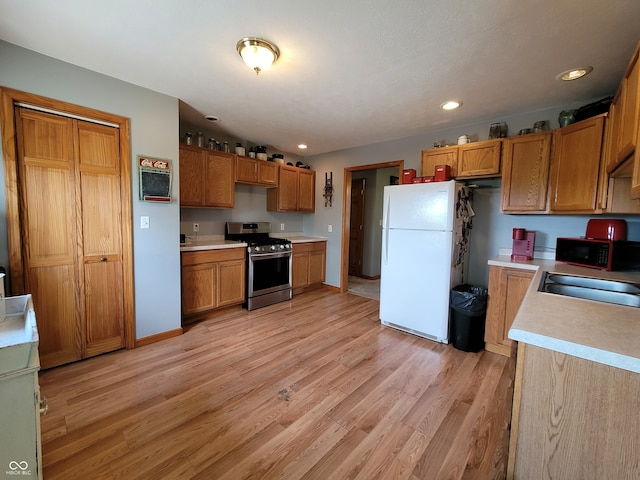 kitchen featuring white refrigerator, gas stove, and light hardwood / wood-style flooring