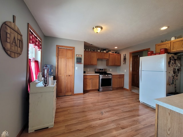 kitchen featuring light hardwood / wood-style floors, stainless steel range with gas stovetop, and white fridge