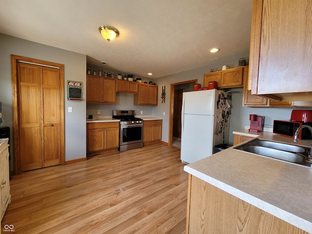 kitchen with stainless steel appliances, sink, and light wood-type flooring