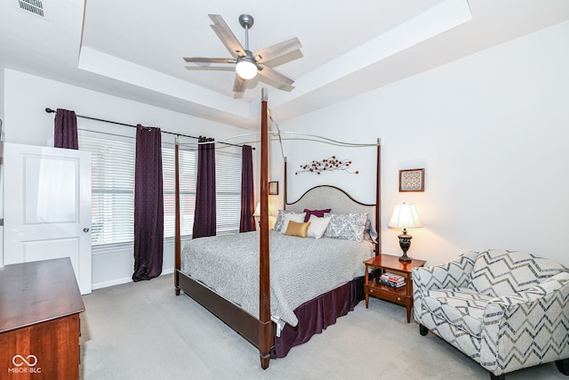 carpeted bedroom with ceiling fan and a raised ceiling