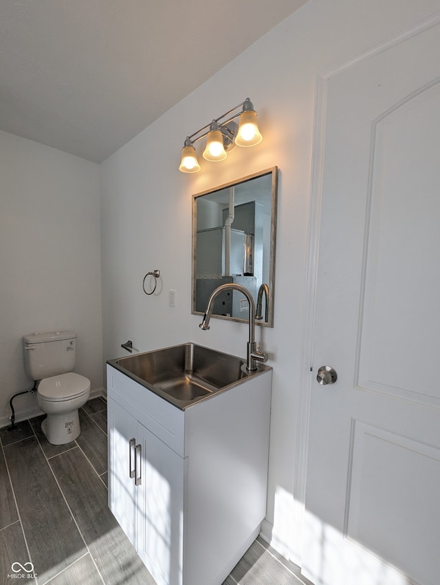 bathroom with vanity, toilet, and wood-type flooring