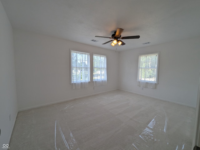 carpeted spare room with a healthy amount of sunlight and ceiling fan