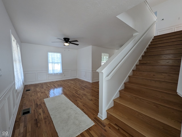 staircase with wood-type flooring and ceiling fan