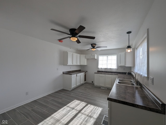 kitchen featuring white cabinetry, hanging light fixtures, dark hardwood / wood-style floors, sink, and ceiling fan