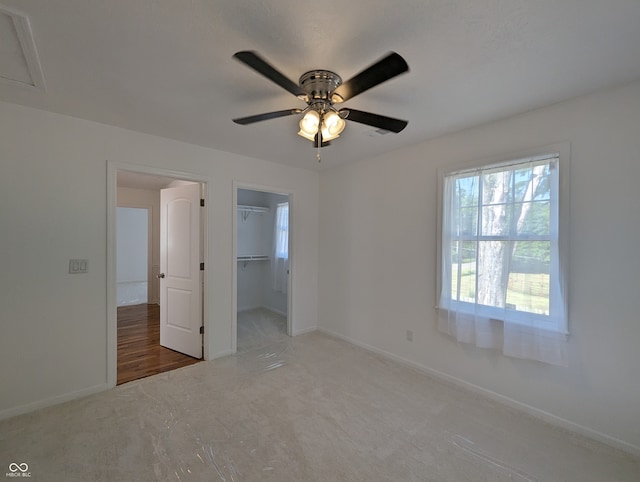 unfurnished bedroom with carpet flooring, ceiling fan, a closet, and a spacious closet