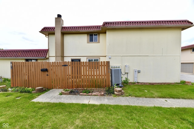 rear view of property with a yard and central air condition unit