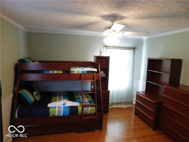 bedroom featuring crown molding, hardwood / wood-style flooring, ceiling fan, and a textured ceiling