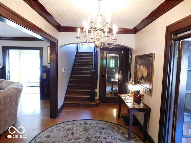 foyer with a chandelier, ornamental molding, and wood-type flooring