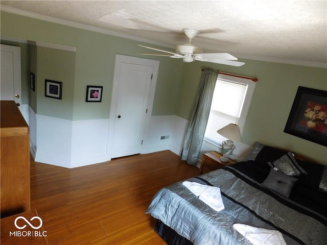 bedroom with ceiling fan, ornamental molding, and wood-type flooring