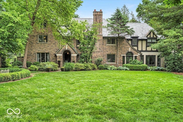 tudor-style house featuring a front yard