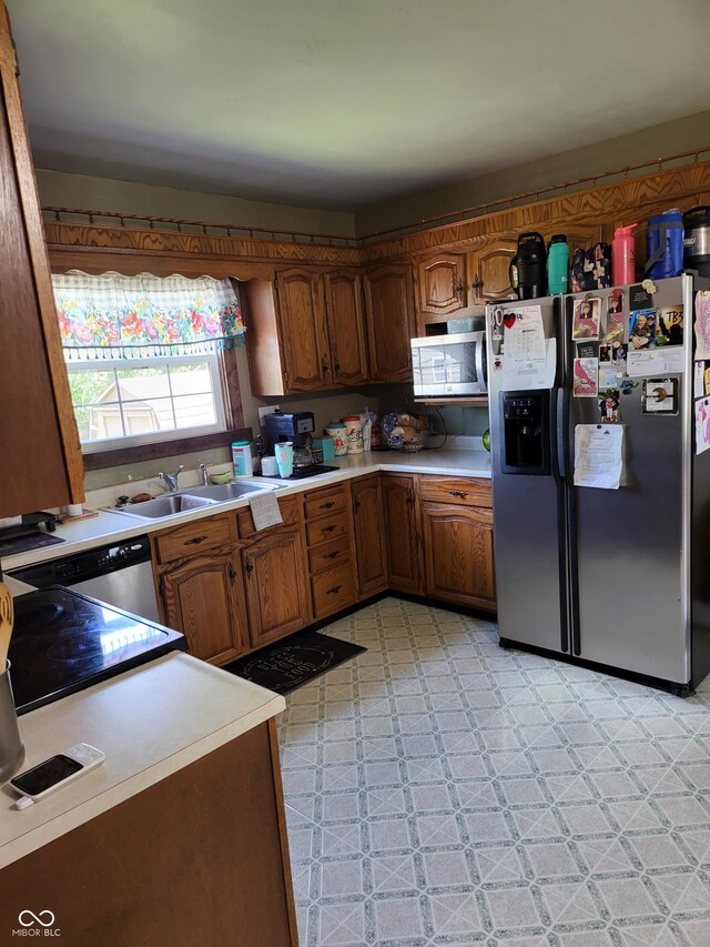 715 5th St, Covington, IN 47932 - kitchen featuring light countertops, stainless steel appliances, a sink, brown cabinetry, and light floors