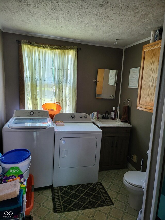 715 5th St, Covington, IN 47932 - laundry room with tile patterned floors, a sink, a textured ceiling, washer and dryer, and ornamental molding