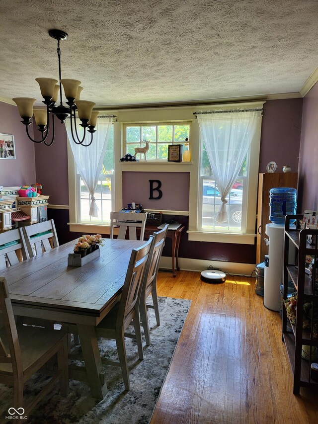 715 5th St, Covington, IN 47932 - dining space with hardwood / wood-style floors, a textured ceiling, ornamental molding, and a chandelier