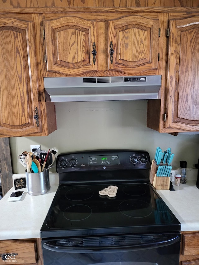 715 5th St, Covington, IN 47932 - kitchen with light countertops, brown cabinetry, black range with electric stovetop, and under cabinet range hood